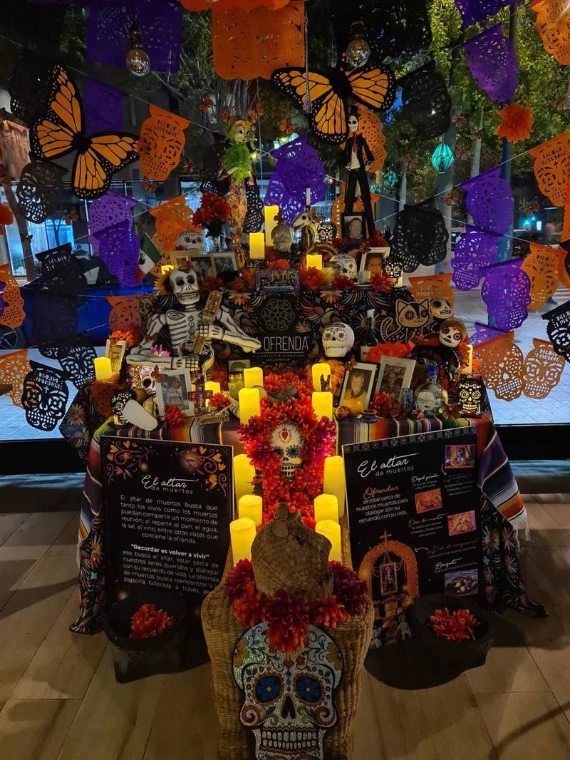 Altar de muertos con cempasúchil, velas y mariposas monarca
